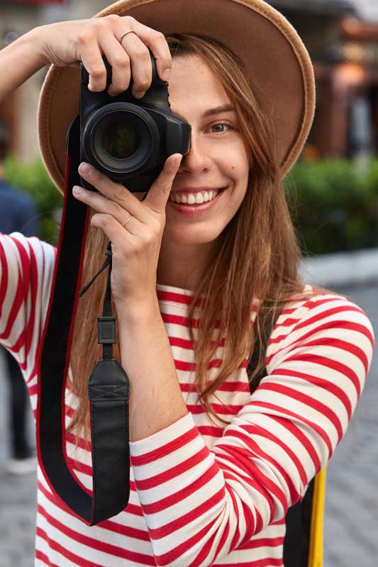 Happy female spends free time on hobby, takes picture of city street on camera during leisure, enjoys weekend travelling, wears headgear and striped jumper, strolls outdoors. People and lifestyle Marketing. Kommunikáció. Kereskedelem. 11